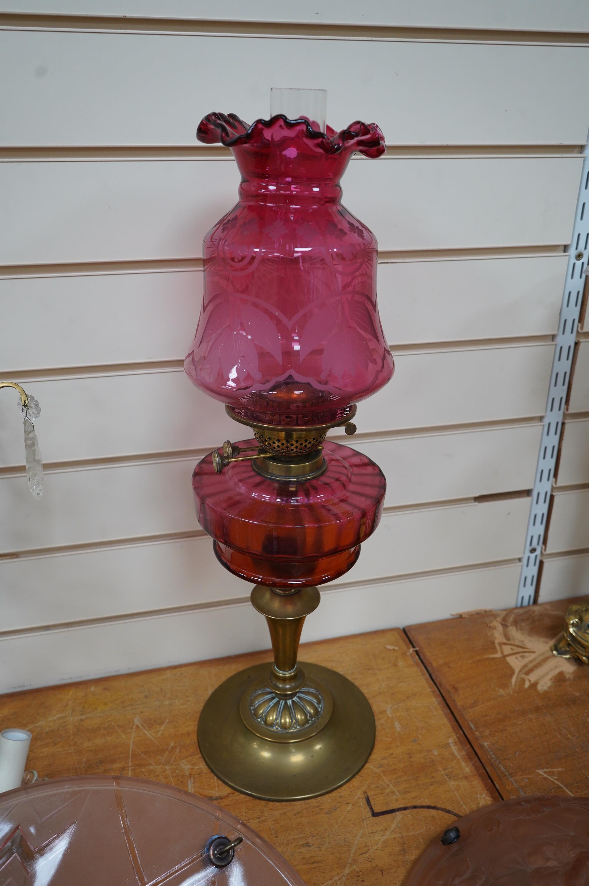 A Victorian oil lamp on brass base with cranberry font, acid etched cranberry shade chimney, overall 62cm high. Condition - good